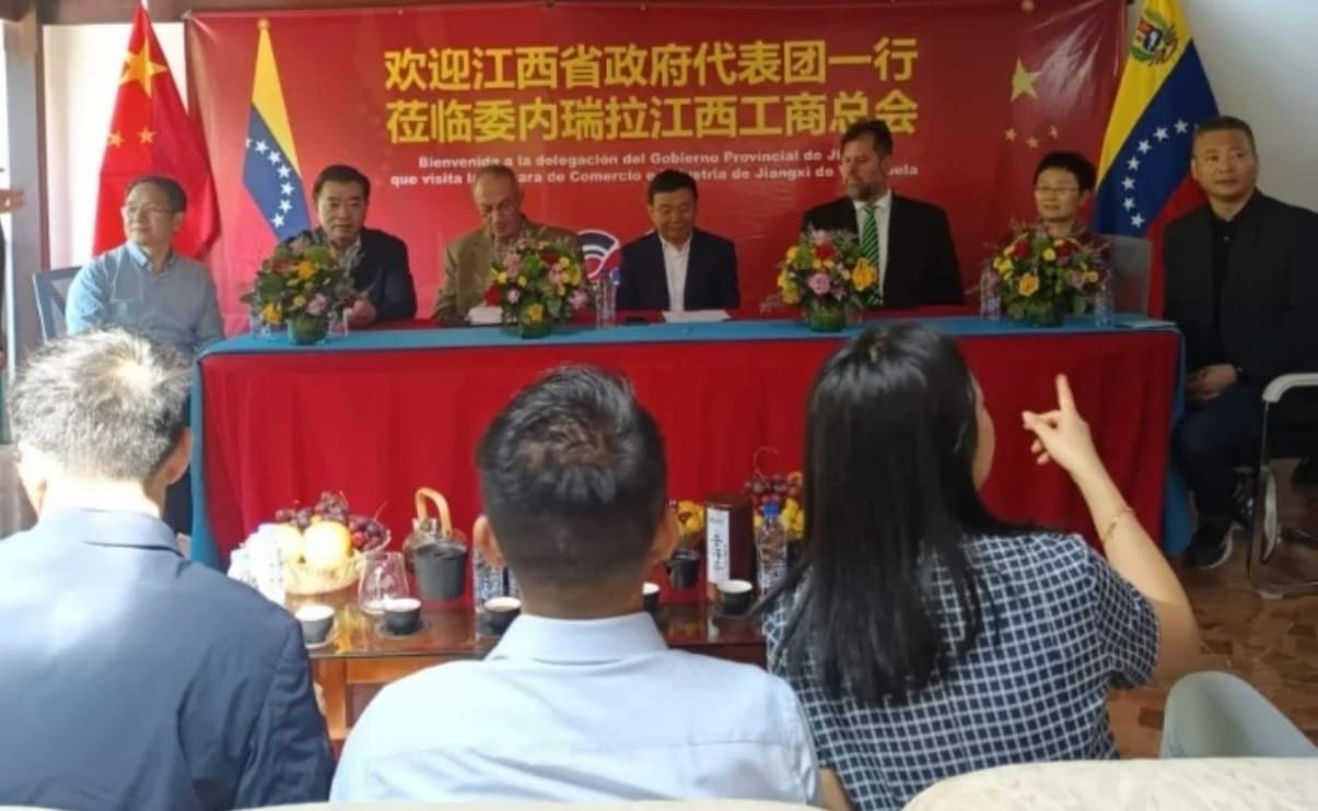 Delegación china y venezolana en mesa de honor durante un encuentro bilateral de comercio.